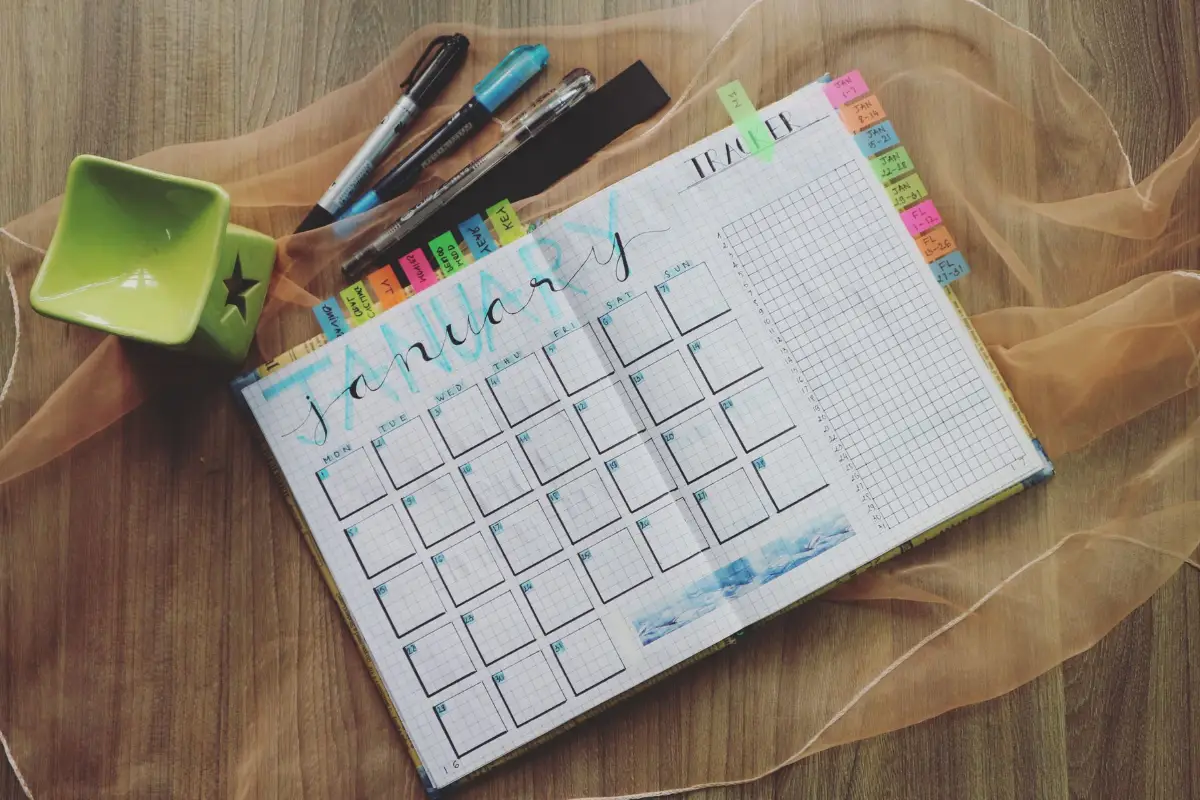 Vue de dessus d'un planificateur de janvier avec des stylos et une tasse verte