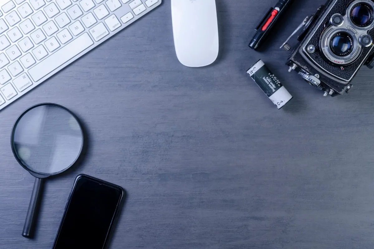 Installation de bureau agencée avec un appareil photo vintage, un clavier, une loupe et un smartphone