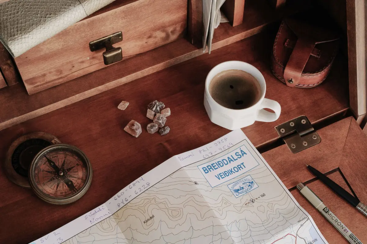 Vue de dessus d'un espace de travail rustique avec une carte, une boussole et une tasse de café